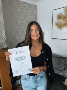 Megan Greig holding certificate with Merit